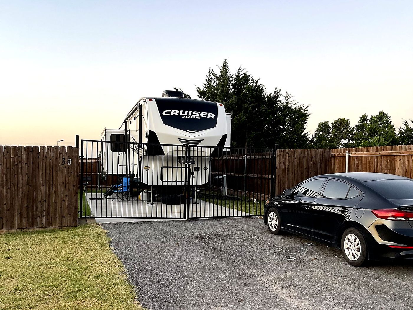 Fifth wheel inside a fenced and gated site at dusk